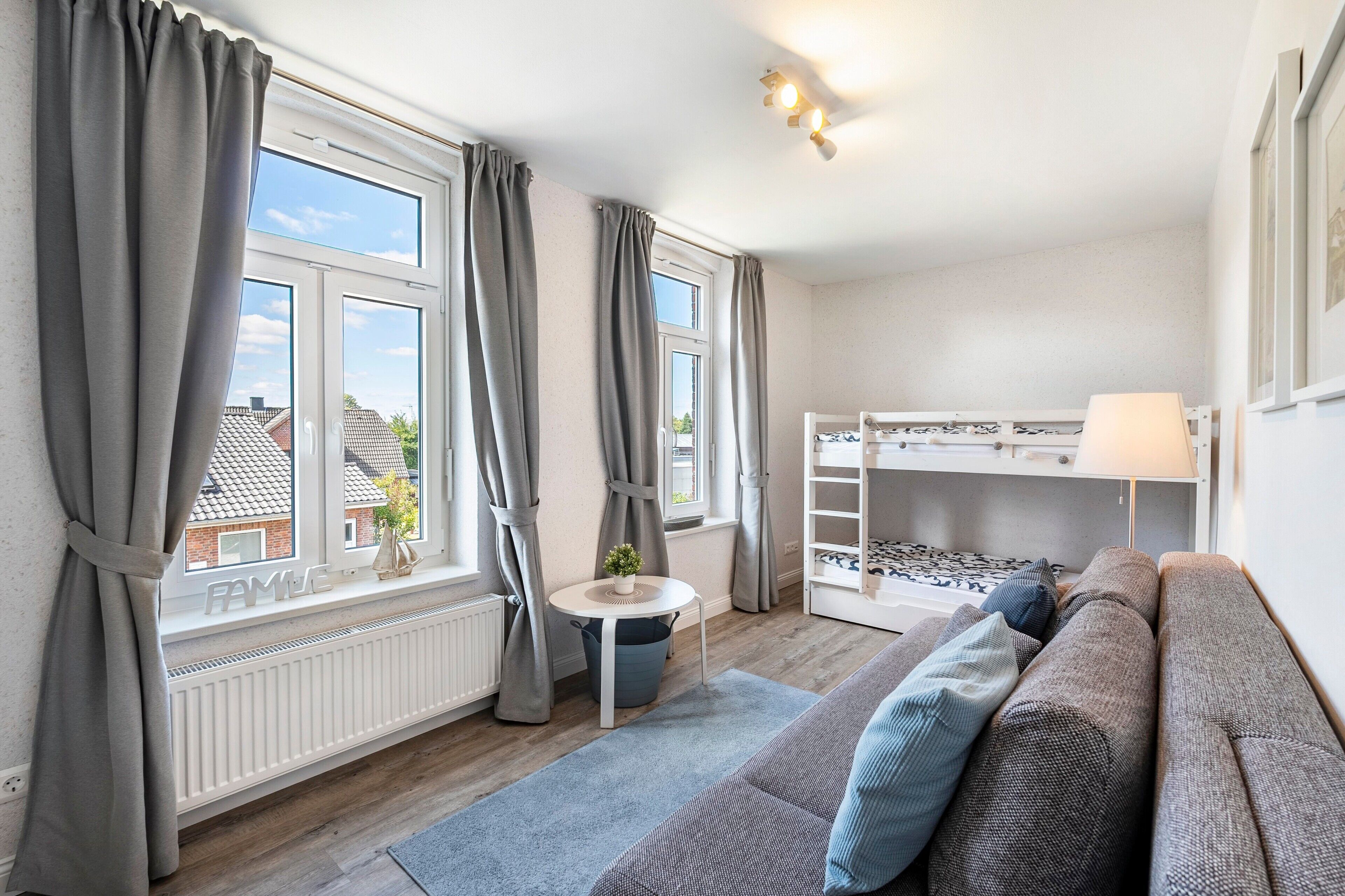 Et værelse med køjeseng, sofa, et lille rundt bord og en radiator.