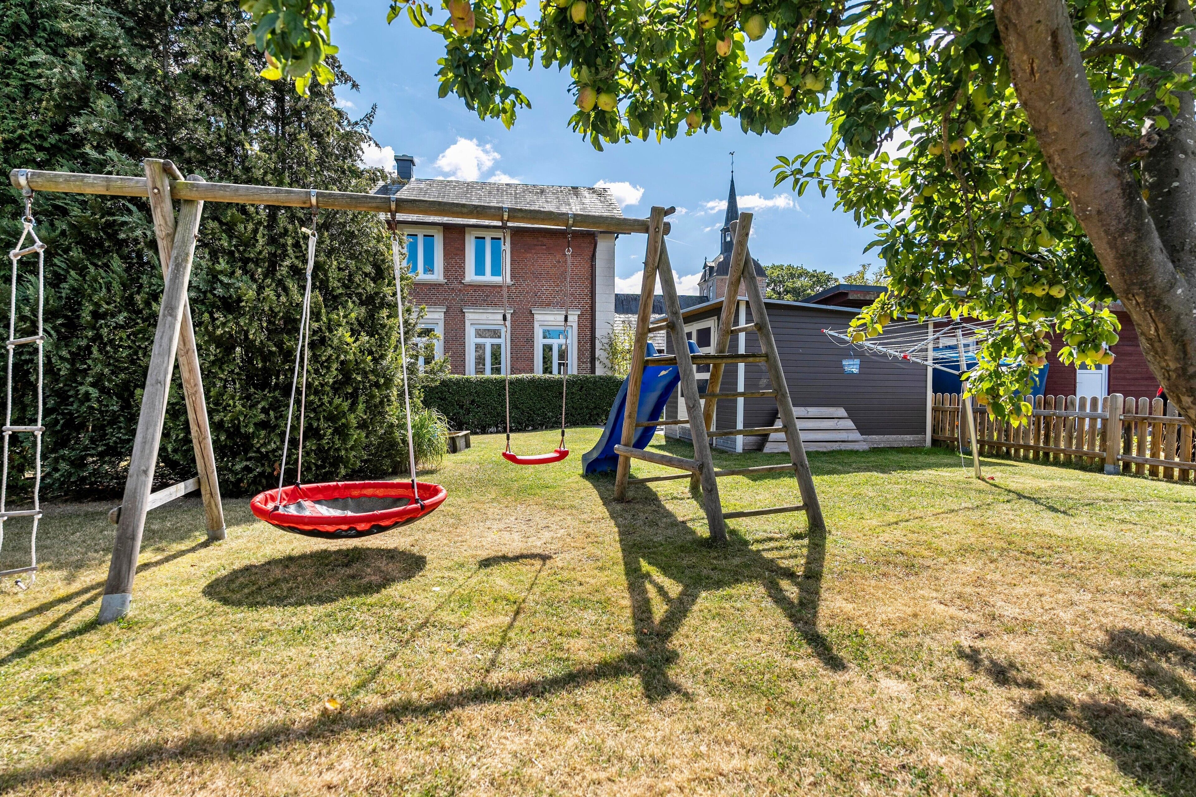 A backyard with a swing set, a slide, and a climbing structure.