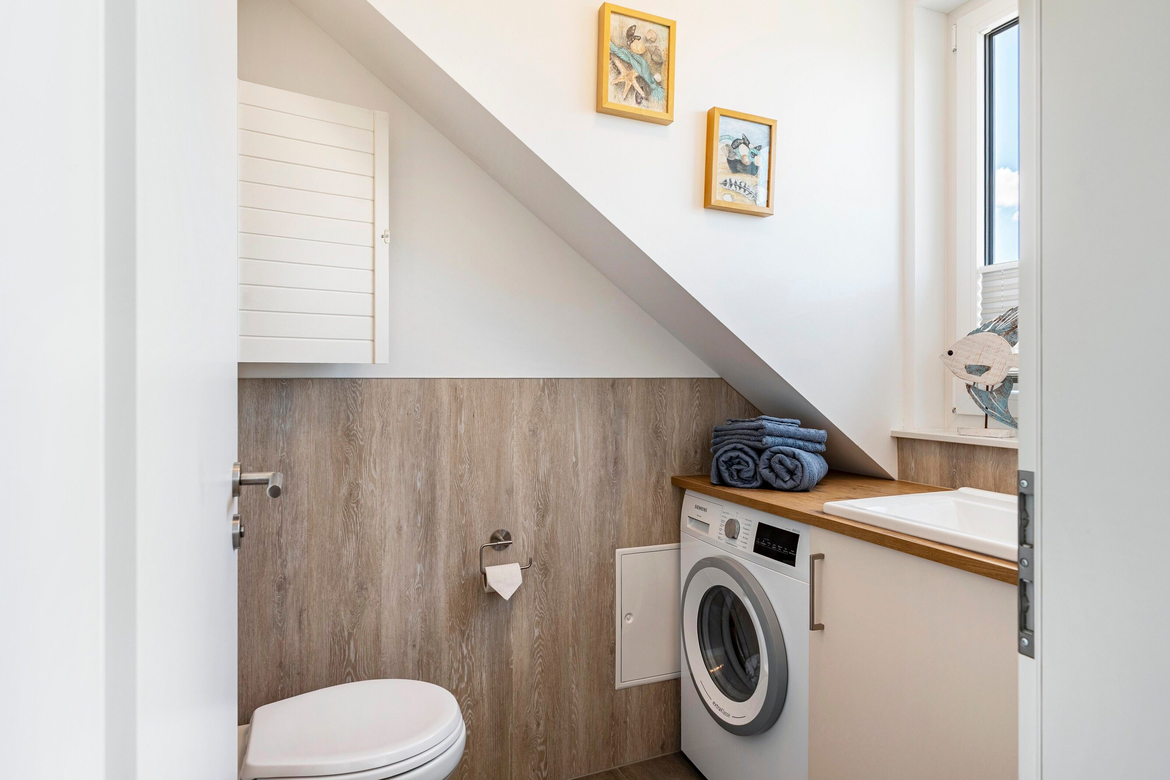 Une petite buanderie comprenant un lave-linge, des toilettes et une petite fenêtre.