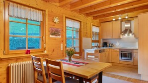 L’intérieur d’une cabane en bois comprend un coin repas, une cuisine et de grandes fenêtres.