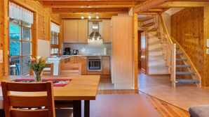 Un intérieur en bois comprenant une table à manger, des chaises, un coin cuisine et un escalier.