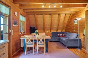 En ombonad träinredning med ett matbord, stolar, en soffa och en golvlampa.