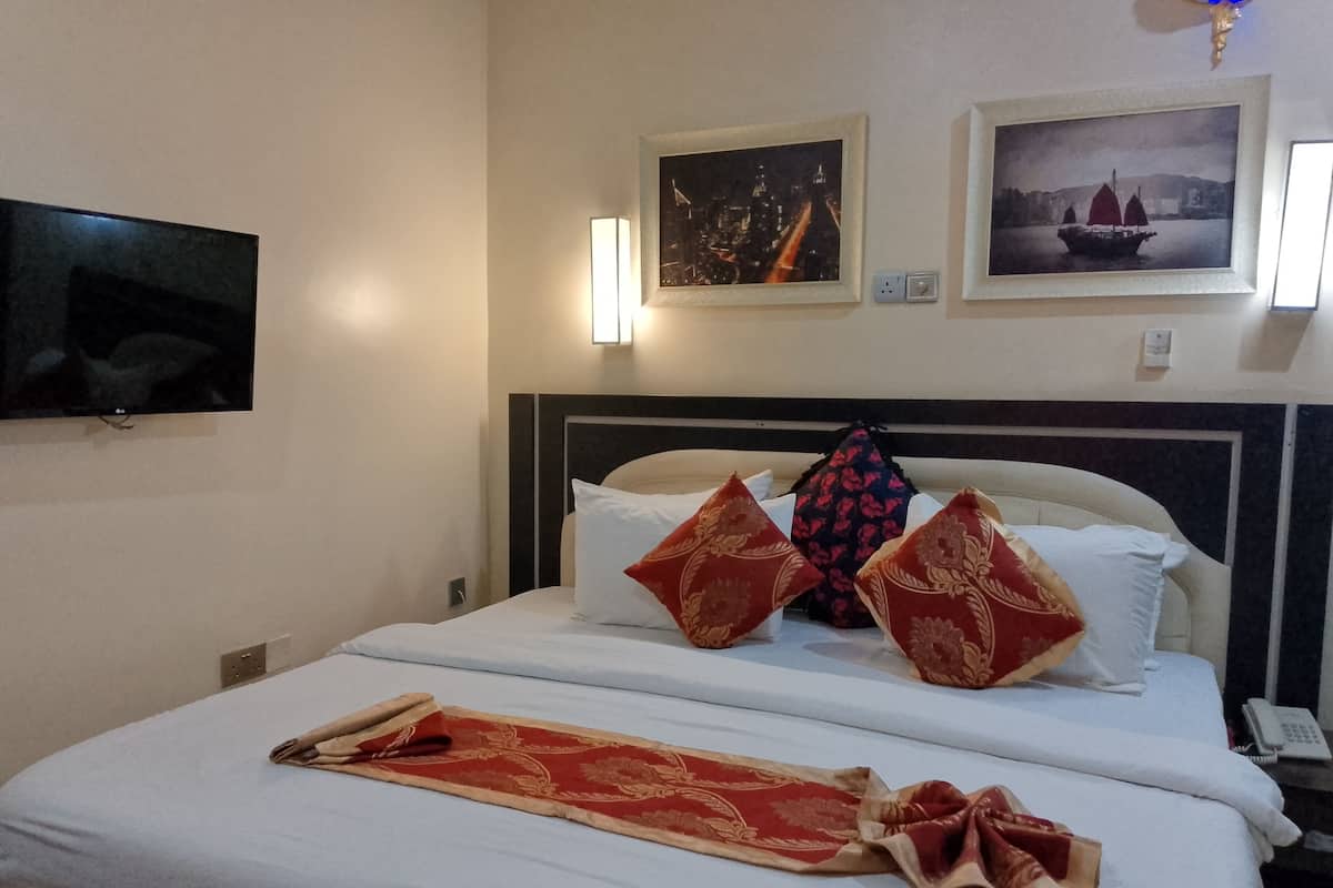 Une chambre d’hôtel comprenant un lit, un téléviseur à écran plat, deux appliques murales et deux tableaux encadrés.