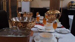 Une table à manger dressée avec des bols dorés, des verres et une lampe décorative.