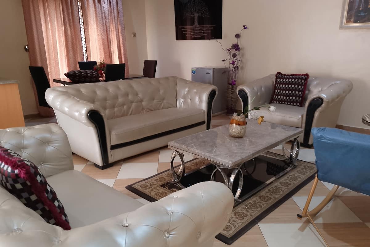 Un salon avec un canapé beige, un canapé blanc, une table basse et un fauteuil bleu.