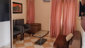 Un salon comprenant un canapé, un fauteuil, une table basse en verre et un téléviseur.