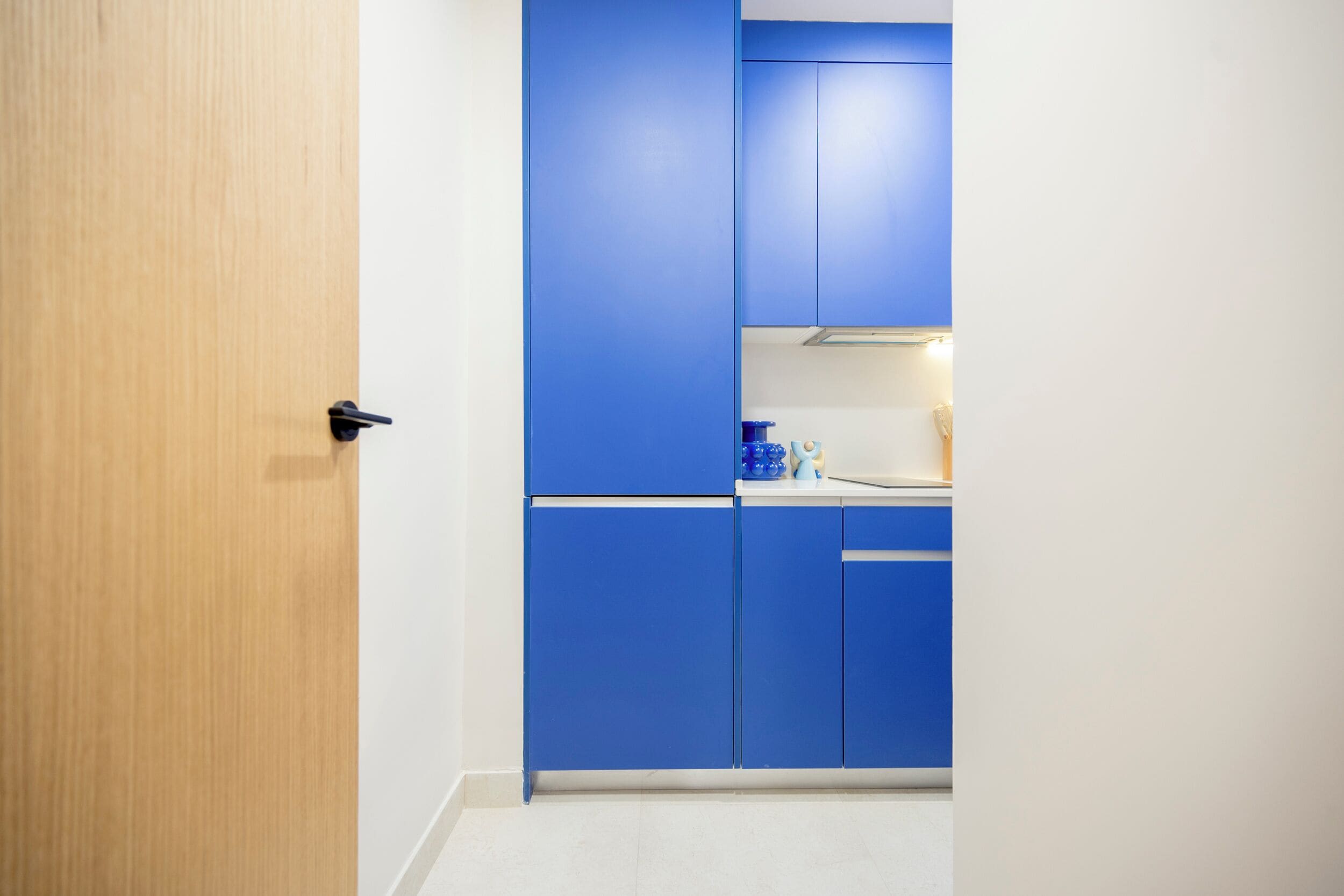 Una cuina moderna amb armaris blaus i una porta de fusta.