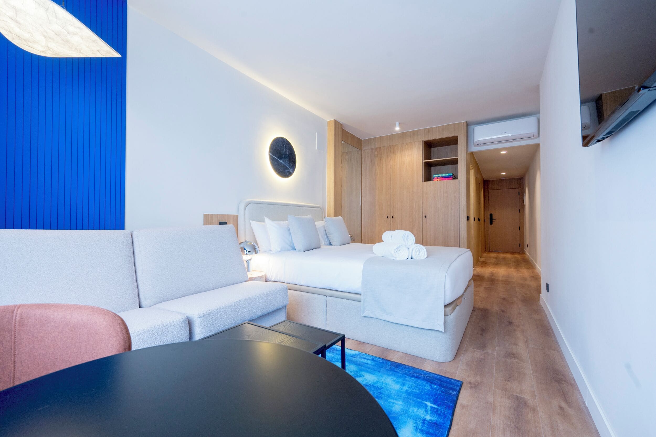 Habitació d'hotel moderna amb un llit, un sofà, una taula i un televisor penjat a la paret.
