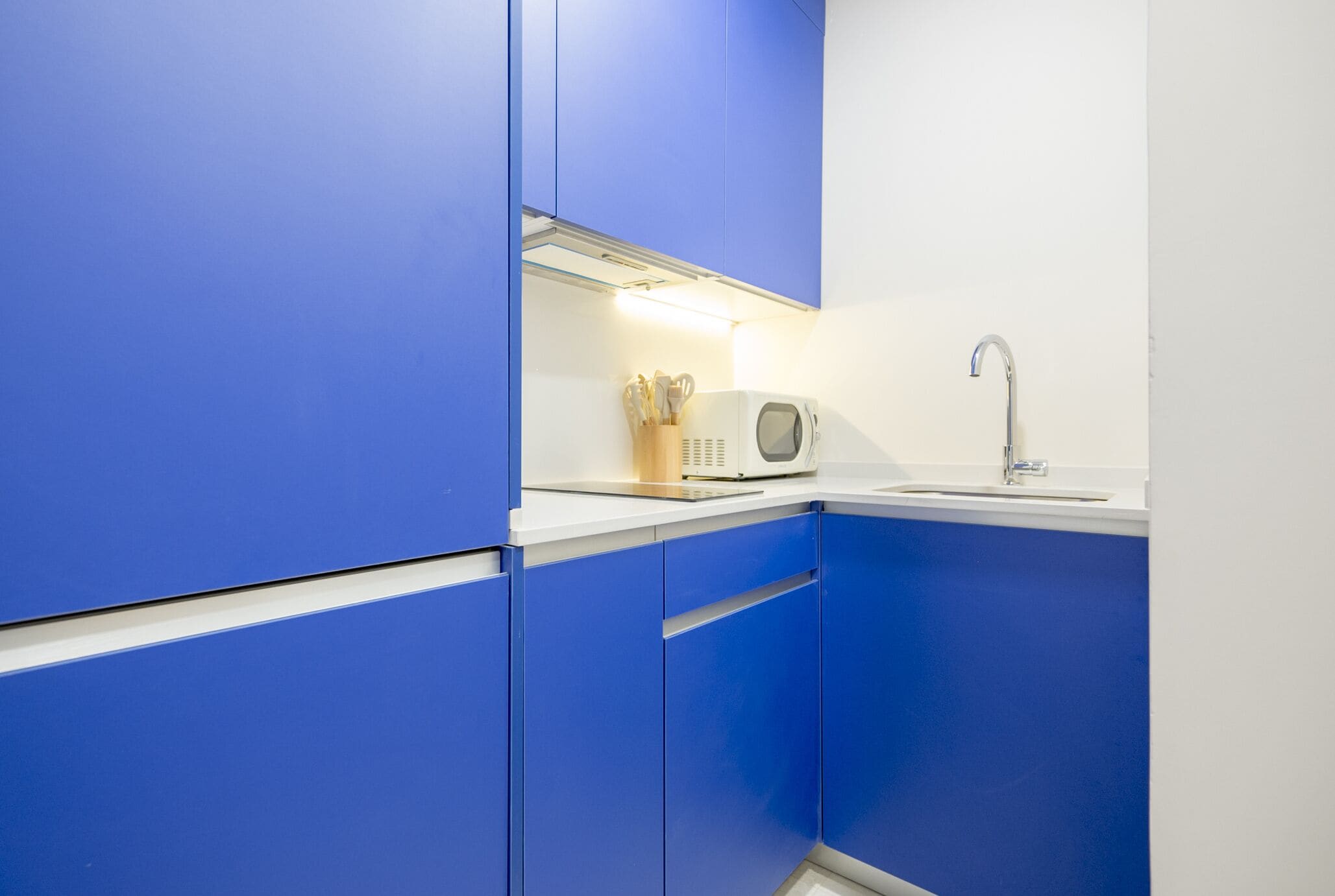 Una cocina moderna con armarios azules, un microondas y un lavamanos.
