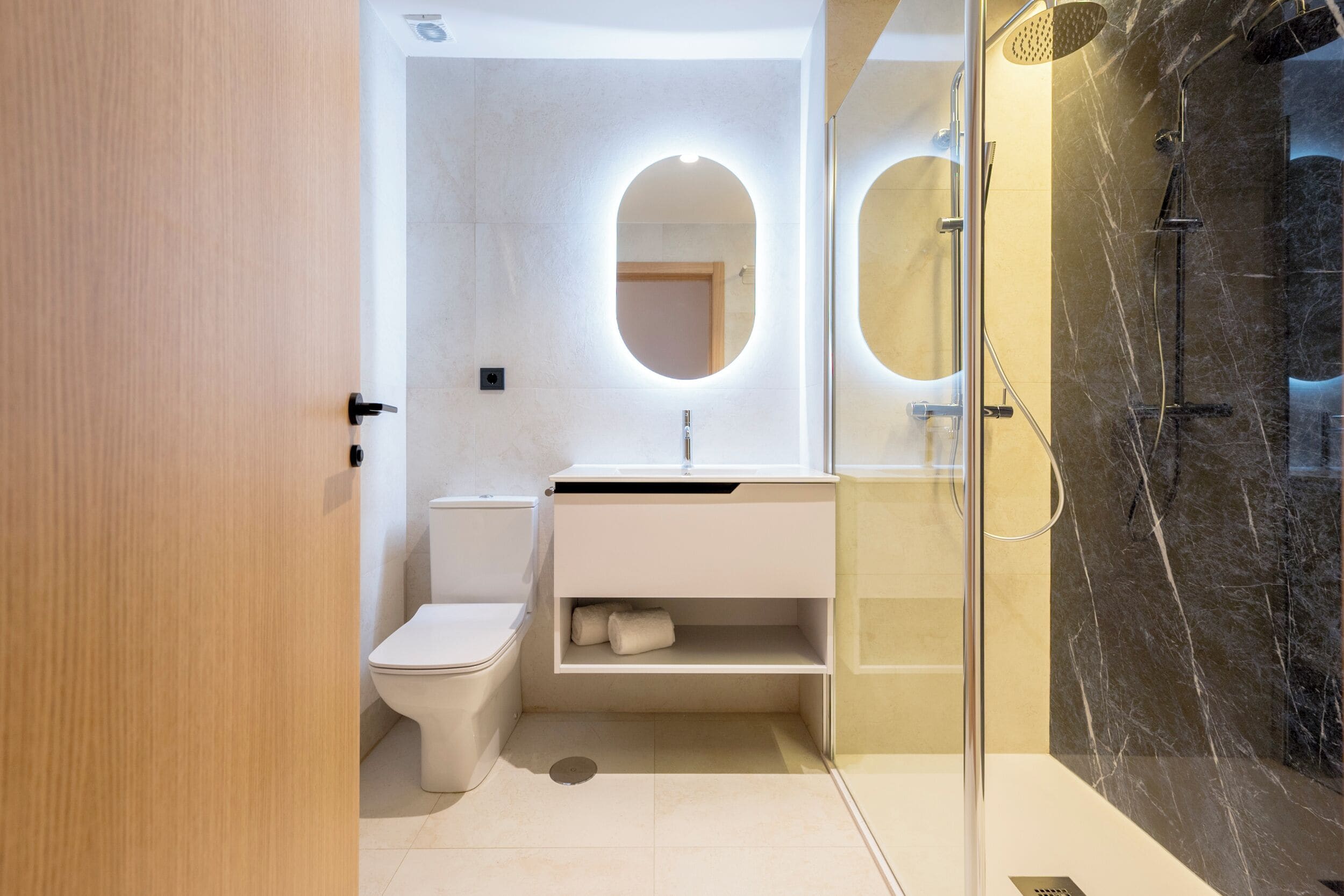 Een moderne badkamer met toilet, wastafel en douche.