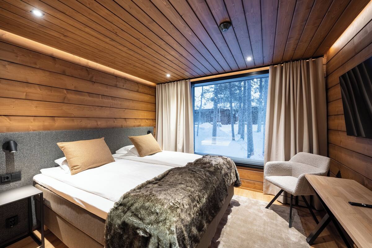 Ein modernes Schlafzimmer mit Holzboden, einem großen Bett, einem Schreibtisch und einem Stuhl.