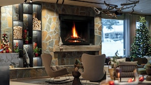A cozy living room with a stone fireplace, comfortable seating, and a Christmas tree. - Wilderness Hotel Kieppi (Saariselkä)