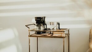 Una mesa de centro de vidrio transparente con una cafetera y un vaso encima.