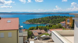 A coastal view with a clear blue sea, a small island with trees, and buildings with red-tiled roofs. - Apartment Mirta 1 (Dramalj)