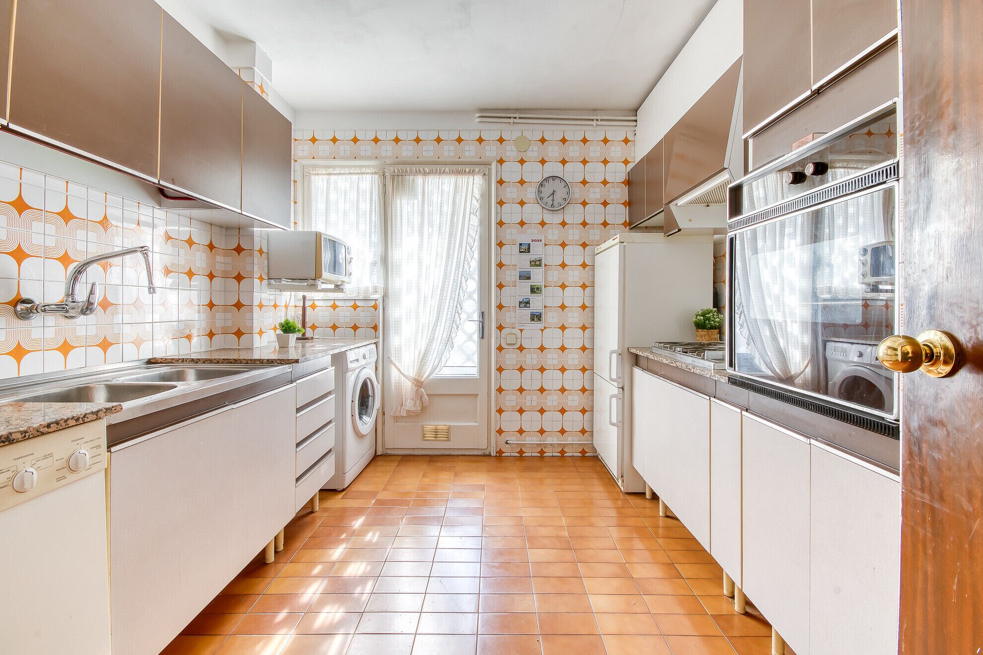 Una cocina estrecha con lavadora, microondas y fregadero.