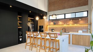 Cocina moderna con una isla central, taburetes de bar y un salpicadero de pared de ladrillo.