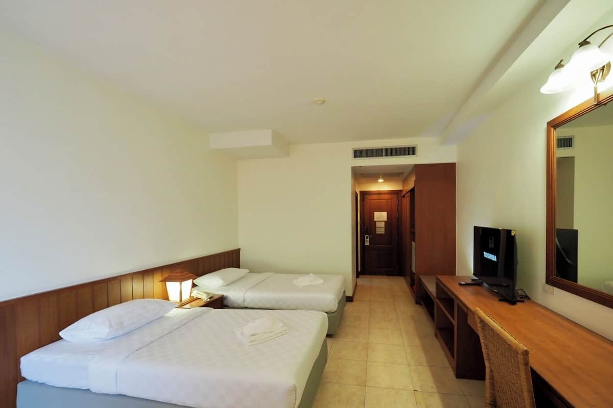 Ein Hotelzimmer mit zwei Betten, einem Schreibtisch und einem Fernseher sowie einem Spiegel.