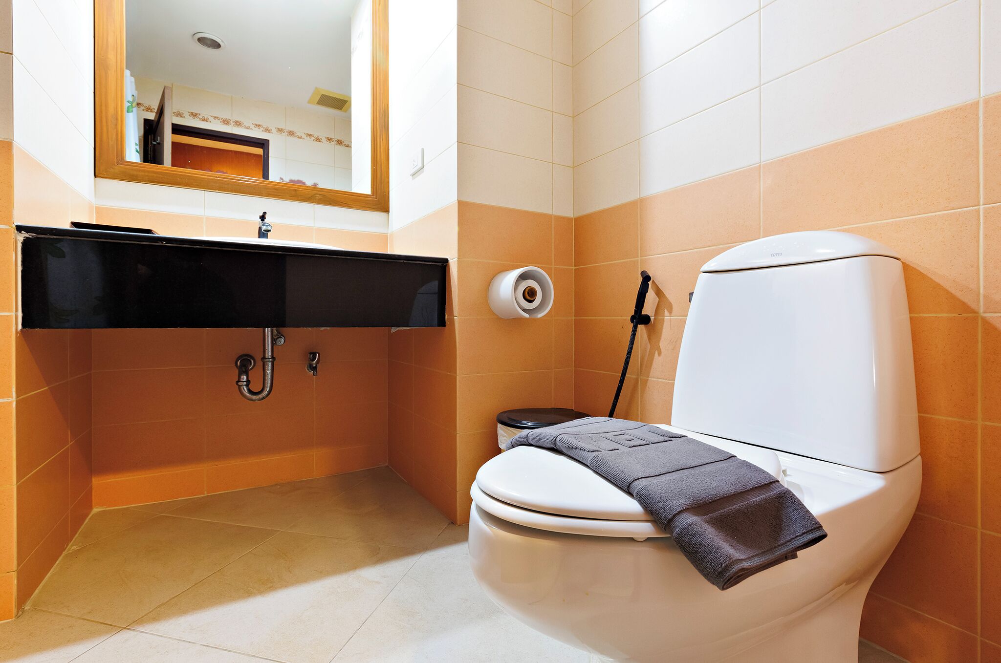 A bathroom with a toilet, sink, and mirror.