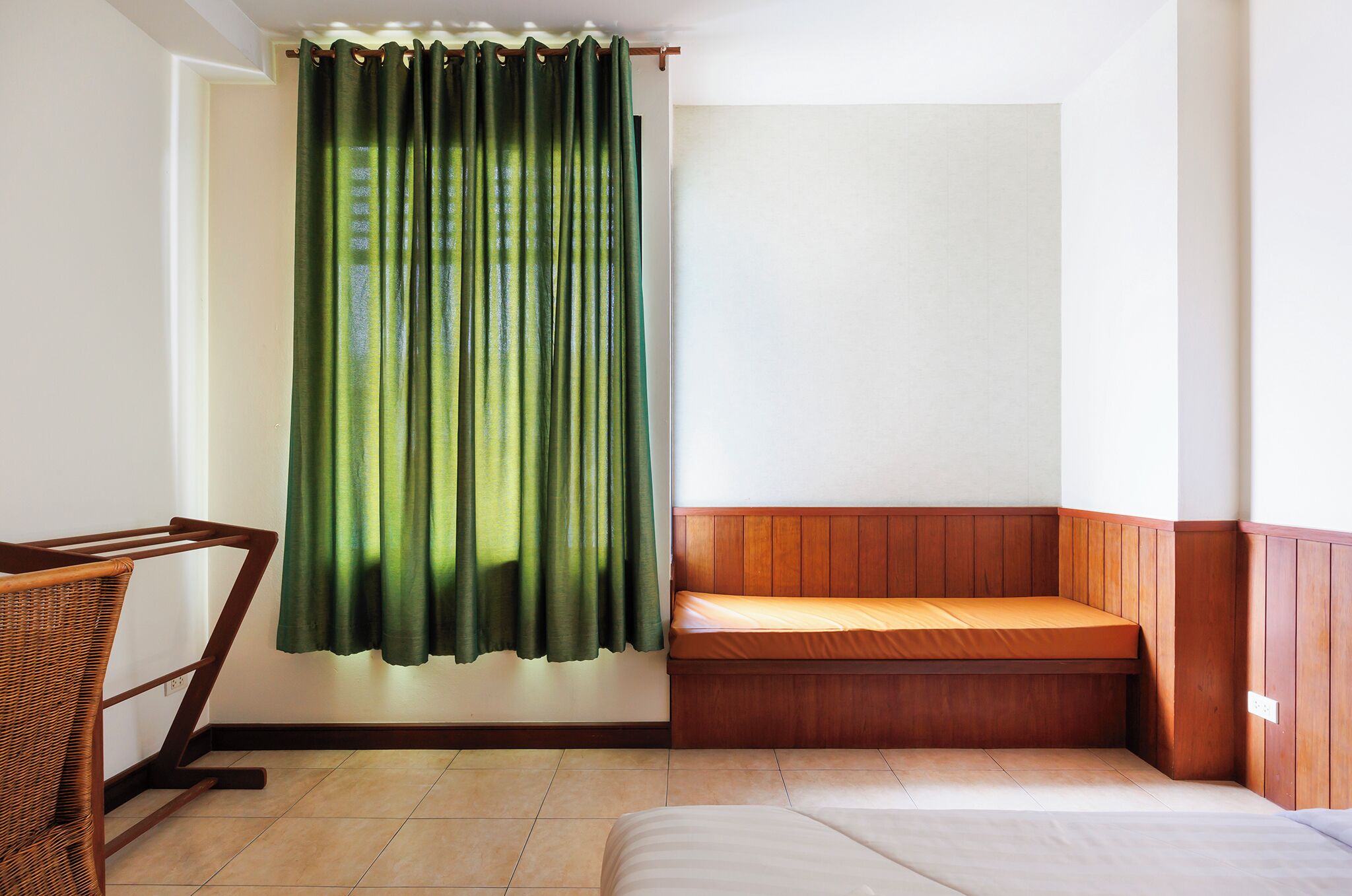 Um quarto com uma cama, um banquinho e uma cadeira.