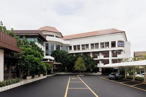A hotel with a parking lot, a covered outdoor area, and a building with multiple windows and balconies.