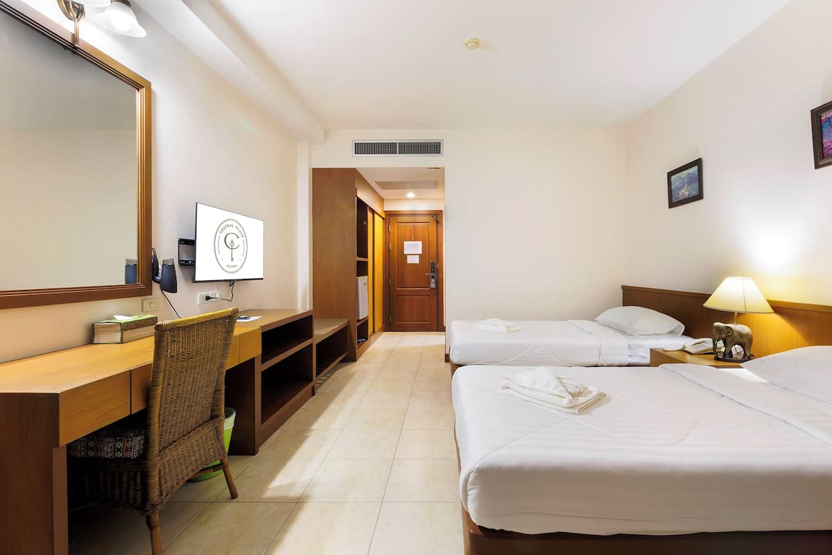 Ein Hotelzimmer mit einem Holztisch, zwei Einzelbetten, einem großen Spiegel und einem Nachttisch mit Lampe.