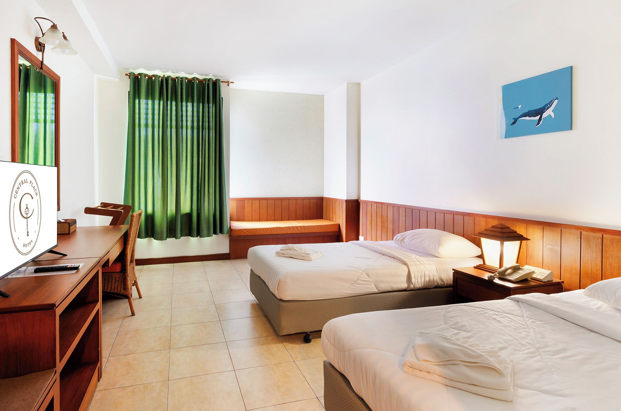 A hotel room with two beds, a desk, a chair, a TV, a lamp, and a painting on the wall.