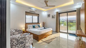 Un dormitorio moderno con una cama grande, un ventilador de techo y vistas al exterior a través de una puerta corredera.