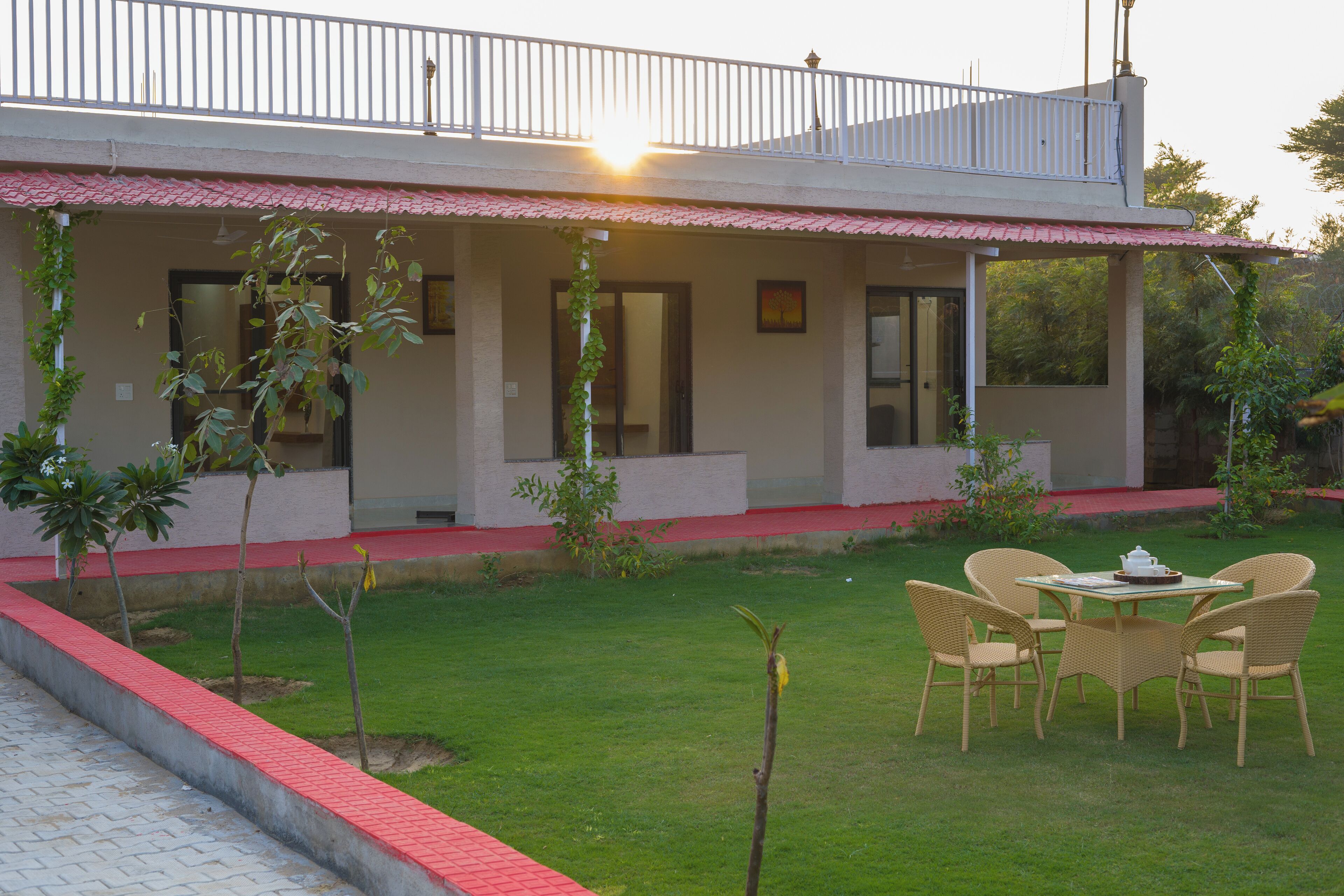 A two-story building with a balcony, a covered patio, and a small garden area with chairs and a table.