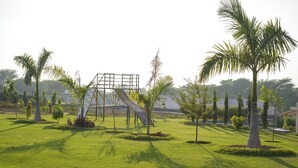 Un parque con un área de juegos, palmeras y zonas verdes.