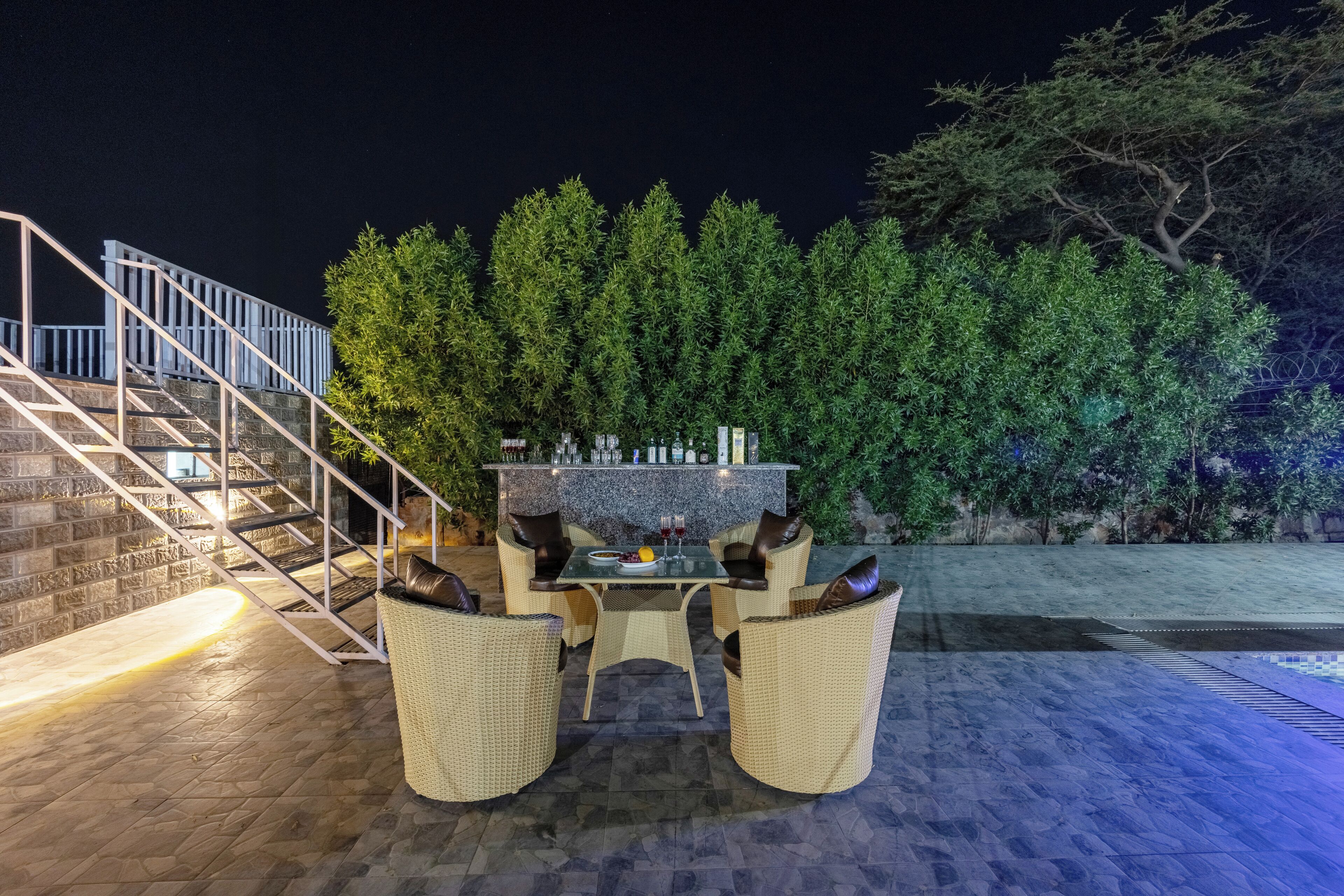 Eine Terrassengaststätte mit Korbmöbeln, einer Steintreppe und einer Bar mit Flaschen.