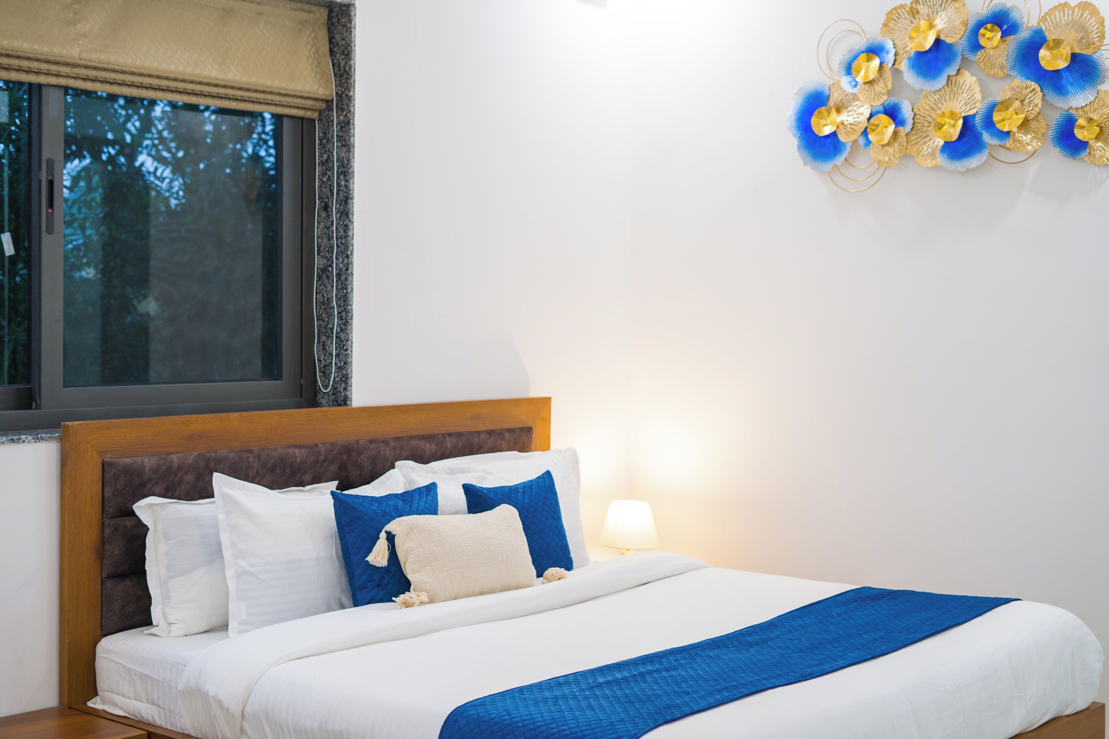 A neatly made bed with white and blue bedding, a wooden headboard, and a wall art piece.