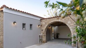 A building with a stone archway, a grey wall, and a tiled roof. - Villa in Kastellákia with Private Pool & BBQ (Rethymno)
