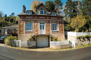 Une maison à deux étages avec un garage, une clôture blanche en bois et une allée.