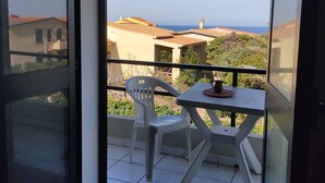 A balcony with a table and chairs, a view of buildings and the sea. - Residenza Agnese Sardegna (La Ciaccia)