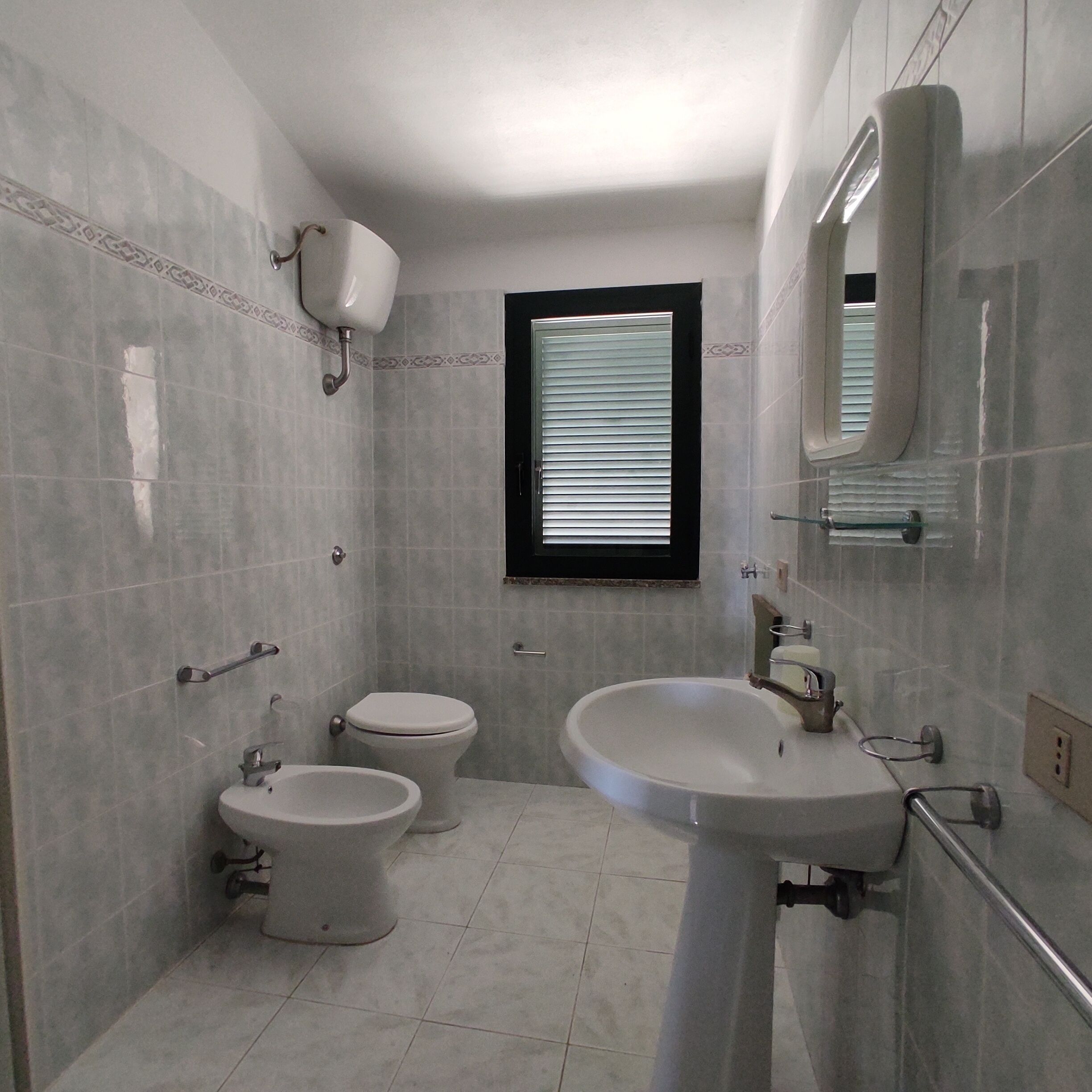 A bathroom with two toilets, a sink, and a window.
