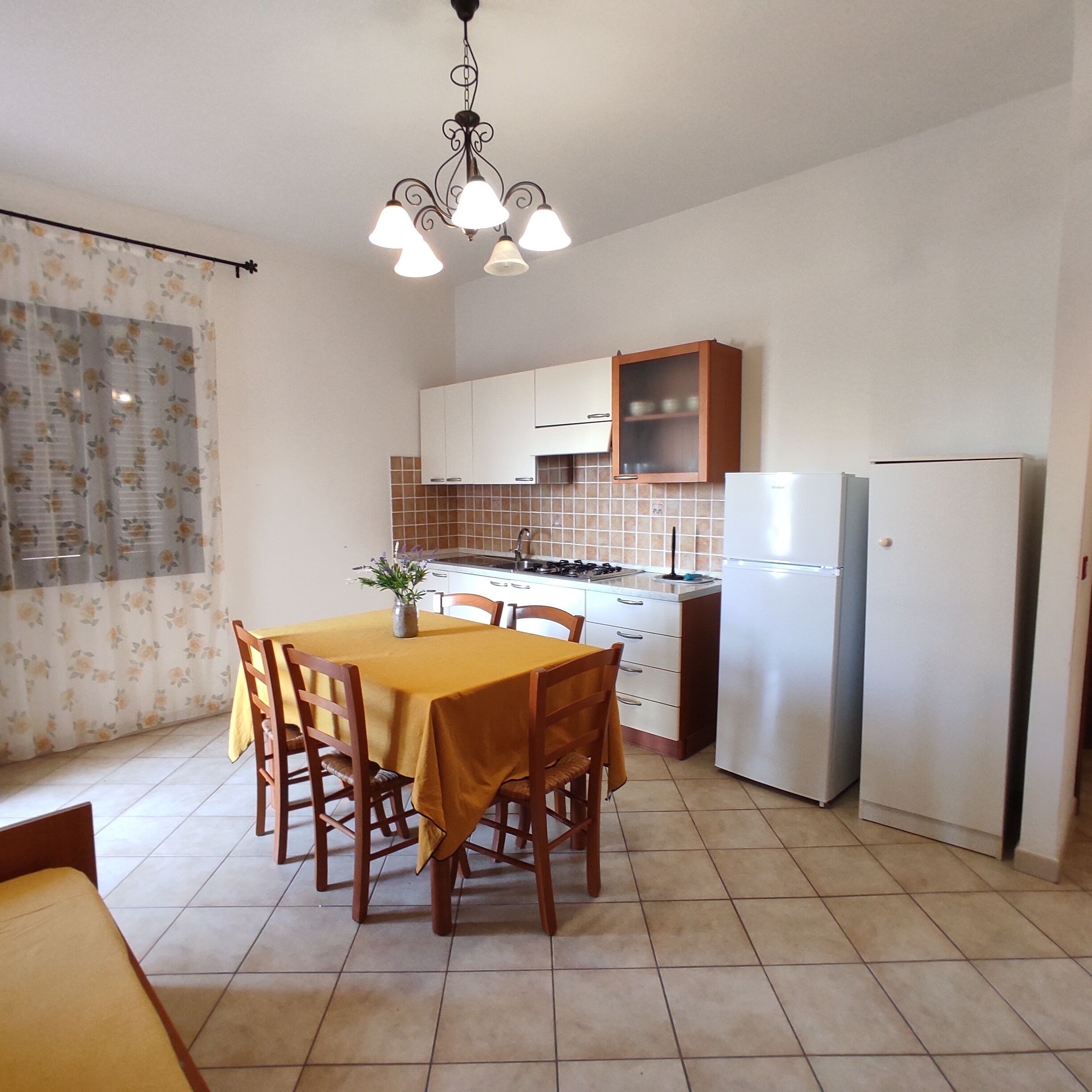 A compact kitchen with a dining area, featuring a table with chairs, a refrigerator, and a stove.