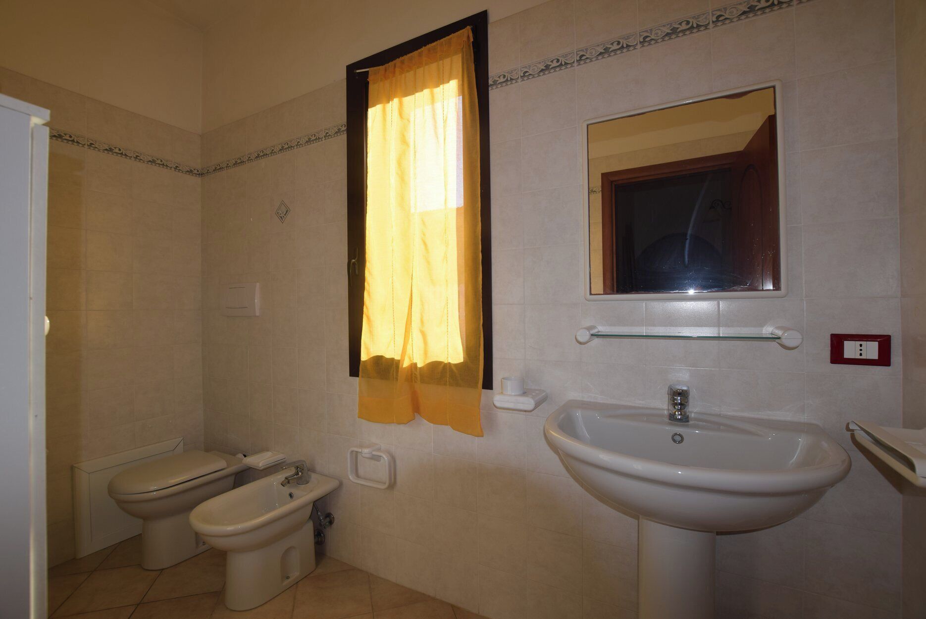 Une salle de bain avec deux toilettes, un bidet, un lavabo, un miroir et un porte-serviettes.