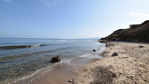A beach with clear water, pebbles, and a rocky shoreline. - Residenza Agnese Sardegna (La Ciaccia)