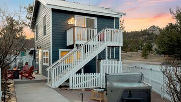 A two-story house with a white porch, a hot tub, and a deck.