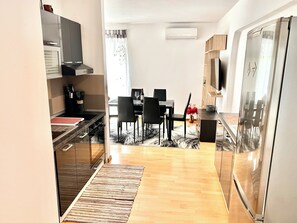 A modern kitchen with a dining area, wooden flooring, and a built-in refrigerator. - Apartman Ana 3 (Dramalj)