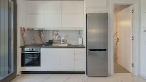 A modern kitchen with white cabinets, a stainless steel refrigerator, and a built-in oven. - Cozy Haven Studio -island Living Paros- (Paros)