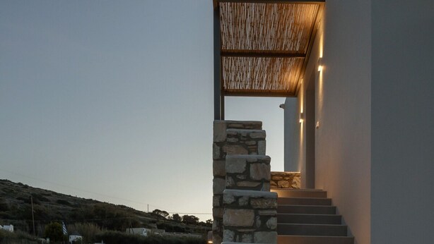 A modern staircase with stone railings and warm lighting, leading to an upper level. - Cozy Haven Studio -island Living Paros- (Paros)