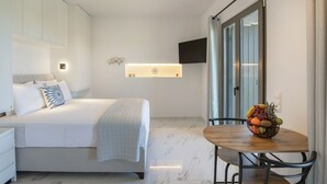 A modern hotel room with a bed, bedside table, and a fruit bowl on a wooden table. - Cozy Haven Studio -island Living Paros- (Paros)