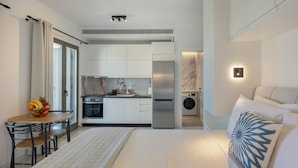 A compact hotel room with a kitchenette, a dining area, and a bed with a decorative pillow. - Cozy Haven Studio -island Living Paros- (Paros)