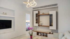 A modern living room with a flat-screen TV, a marble coffee table, a sofa, and a decorative orchid plant. - Cozy Haven -island Living Paros (Paros)