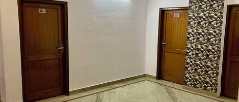 Un pasillo con dos puertas de madera identificadas con los números 201 y 202, un suelo de mármol y una pared con diseño de piedras.