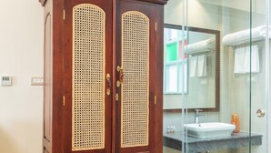 Egy díszes, faragott mintákkal ellátott fa szekrény, egy üvegfalas zuhanykabin, valamint egy mosdókagylóval és törölközőtartóval felszerelt fürdőszoba.