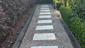A pathway with stepping stones leading through a garden area, bordered by gravel and bordered by hedges and a wooden fence. - Eton Cottage: Central Boutique Stay (East Toowoomba)