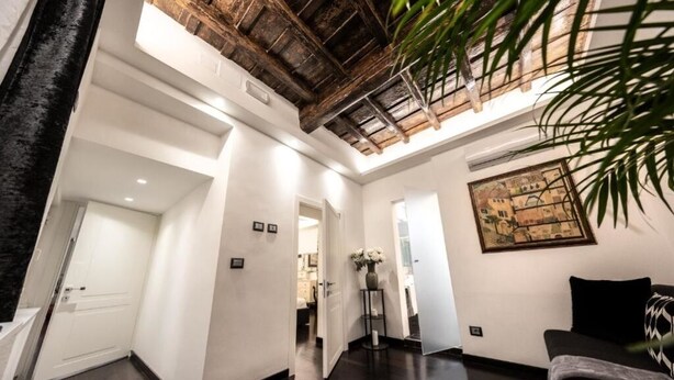 Amplia sala de estar con techo alto, piso de madera oscura, un sofá negro y una obra de arte enmarcada en la pared.