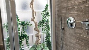 Un baño con puerta de cristal, una escultura de madera y una ducha con panel de control.